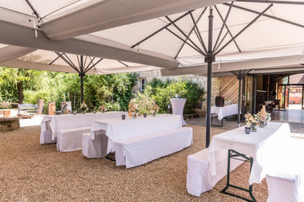 Kernmühle Roßtal avec des parasols SCHATTELLO blancs Une cour idyllique avec des parasols blancs devant un bâtiment en briques rustique