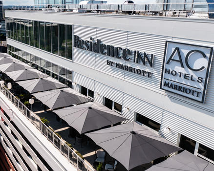 Terrasse moderne avec des parasols noirs devant une façade vitrée.