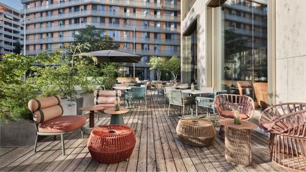 Hôtel Renaissance Tower avec parasols FILIUS bruns Une terrasse confortable à la tombée de la nuit avec des sièges, des parasols et un éclairage aux bougies