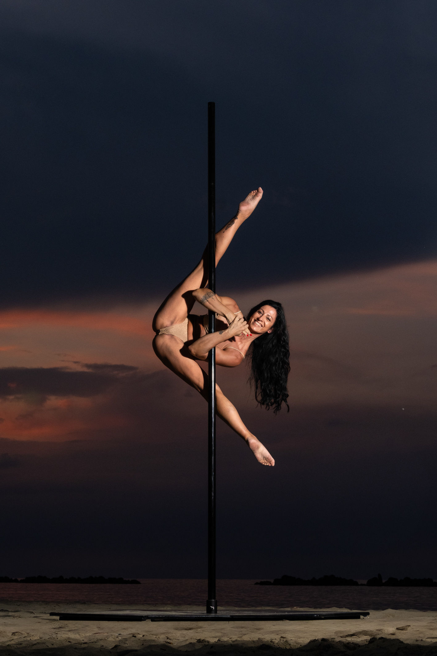 Ballerina in estensione orizzontale su un palo al tramonto