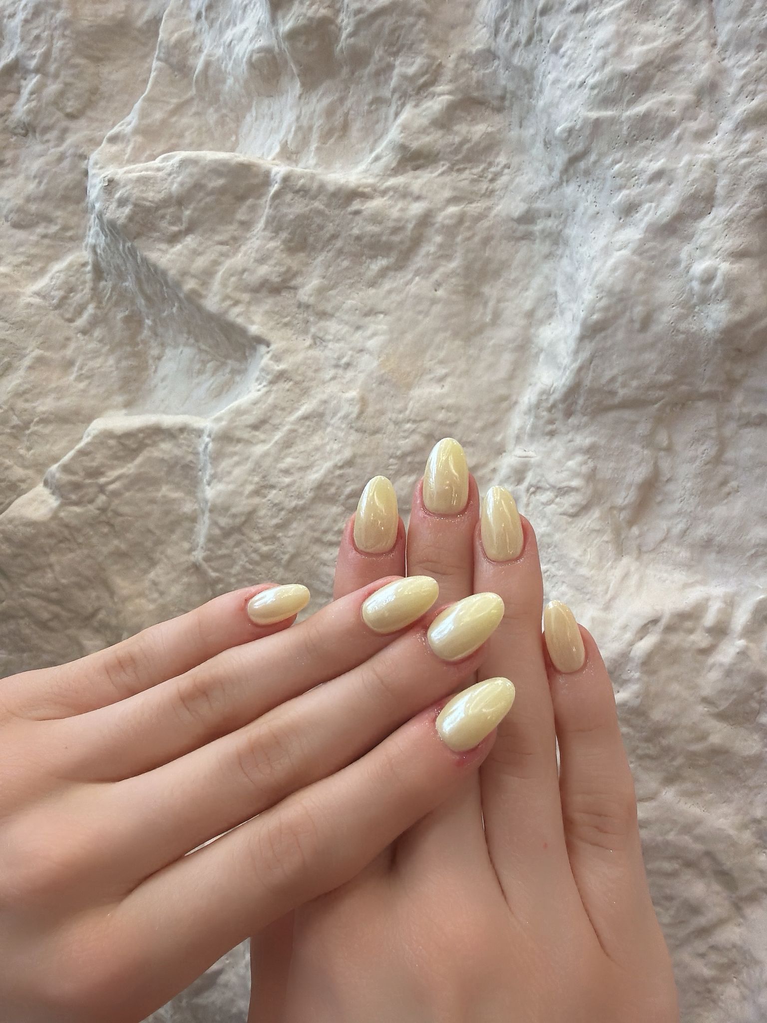 Glossy almond nails in a soft pearl butter yellow finish