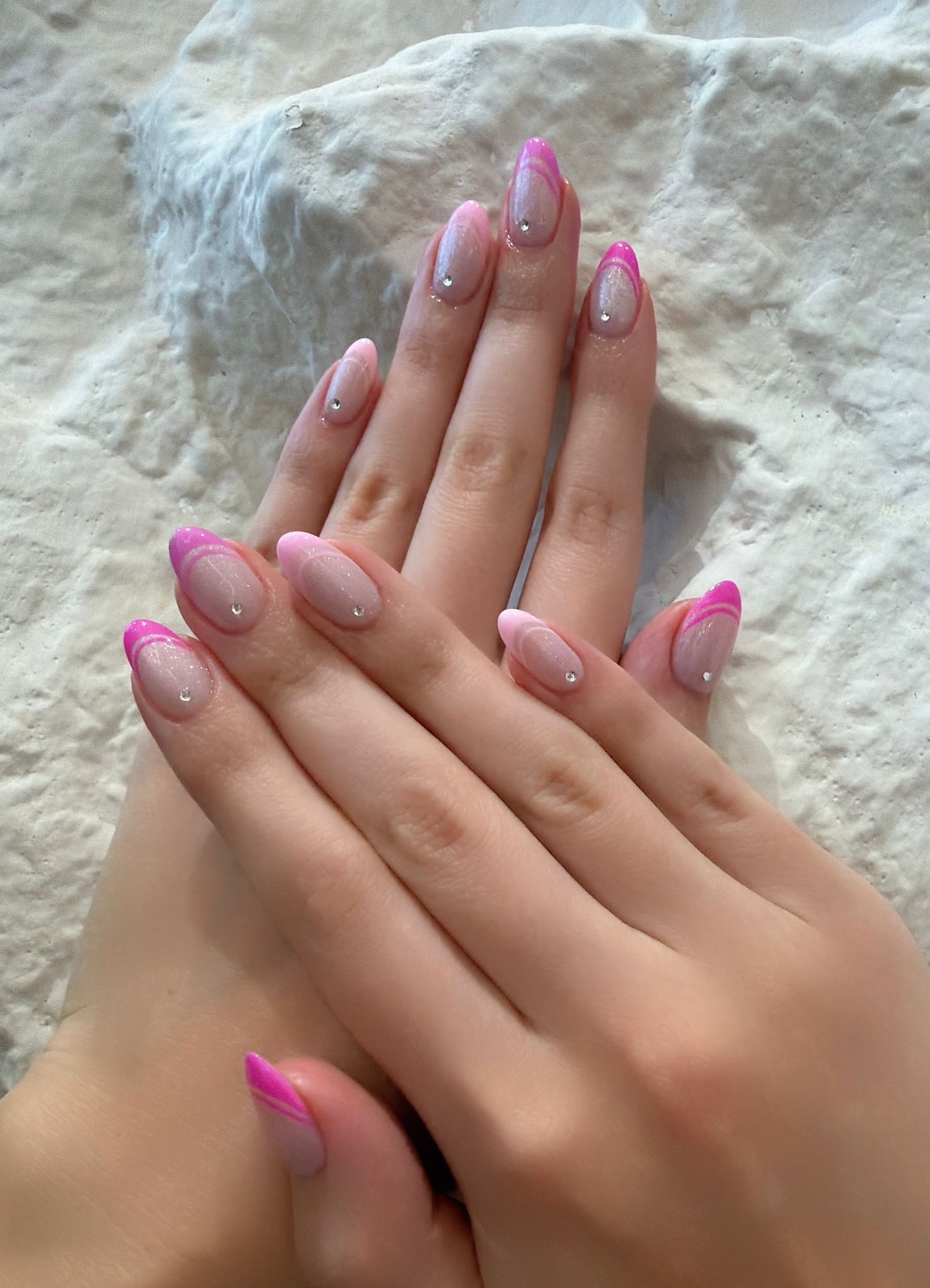 Pink French almond nails with subtle shimmer and crystal accents
