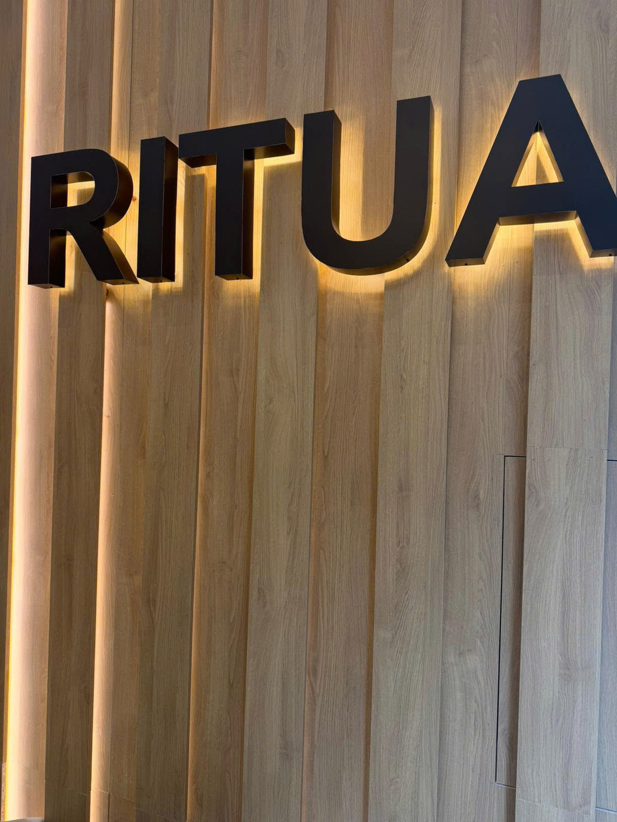 RITUA HOUSE illuminated salon sign on warm wood wall