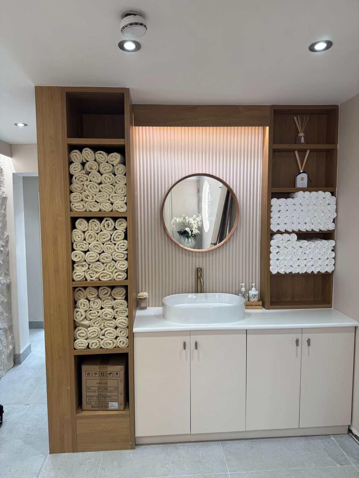RITUA HOUSE wash area with neatly rolled towels and warm wood shelving