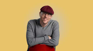 Daniel Lassak Mann mit roten Hut sitzt auf einem Stuhl