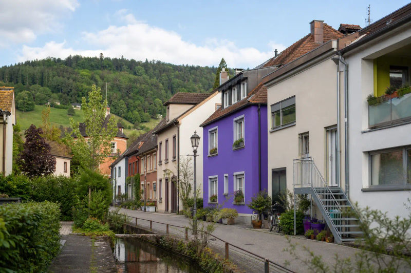 Freiburger Wohnstraße mit Bächle und Hügeln im Hintergrund