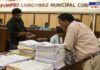 Officials reviewing tender documents at the Pimpri Chinchwad Municipal Corporation office. Stacks of files on the table highlight the volume of paperwork involved in the tender process. Concerns have been raised over alleged irregularities in the tendering system.