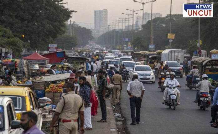 A busy urban street congested with traffic and street vendors. Numerous people walk along the roadside, while makeshift stalls selling fruits and other goods occupy the footpath. Vehicles, including cars, bikes, and auto-rickshaws, struggle to navigate through the crowd. Police officers are present, monitoring the situation. The background features tall buildings and streetlights, indicating a growing cityscape.