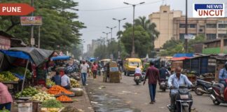 A busy street in Pune with fruit and vegetable vendors occupying the footpath. Stalls with fresh produce such as oranges, cabbages, and leafy greens line the sidewalk. Pedestrians walk alongside vehicles, including scooters and a yellow van, on a road scattered with waste. Buildings and trees are visible in the background,showcasing a typical urban Pune market scene.