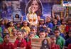 A group of Indian school children in colorful uniforms gathers to celebrate astronaut Sunita Williams' return to Earth. A young girl dressed as an astronaut, adorned with a flower garland, stands at the center, symbolizing Williams. Students hold posters and banners with Williams' images and messages like "Welcome Home" and "Sunita Williams Returns Home." The background features a large portrait of Sunita Williams, decorated with flowers, enhancing the festive and inspiring atmosphere of the event.