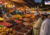 A bustling market during Ramadan, illuminated with decorative string lights. A variety of dates and dried fruits are neatly arranged in trays at a stall. Two men in traditional Islamic attire examine the dates, while a shopkeeper organizes the produce. Other fruits like bananas, peaches, and oranges are also displayed, adding to the vibrant atmosphere of the evening market.