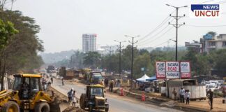 A road construction and encroachment removal scene on Pune-Satara and Pune-Solapur Road. Bulldozers and workers are actively clearing the roadside, with people walking and observing the operation. A road sign indicates directions for Pune, Satara Road, and Solapur Road. Buildings and greenery are visible in the background.