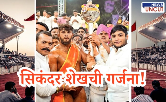 Victorious wrestler Sikandar Sheikh proudly holding a silver mace surrounded by cheering supporters, with a traditional rural wrestling arena and crowd in the background. Bold Marathi text in the center reads 