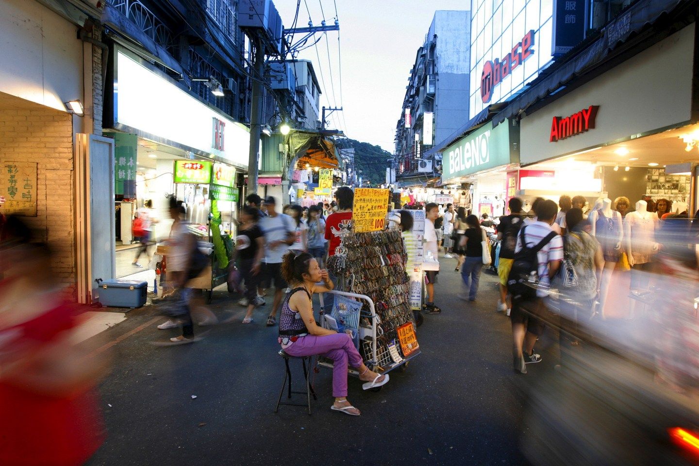A woman sits beside her stall at the Shilin night market in Taiwan