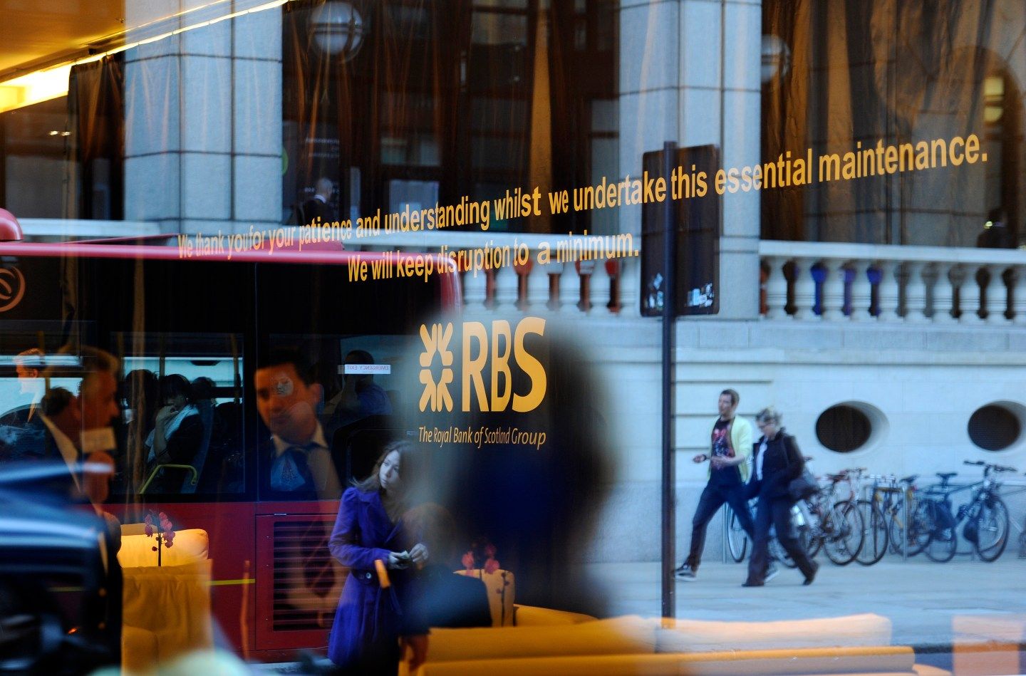 Pedestrians are reflected in the window of a Royal Bank of Scotland building in the City of London