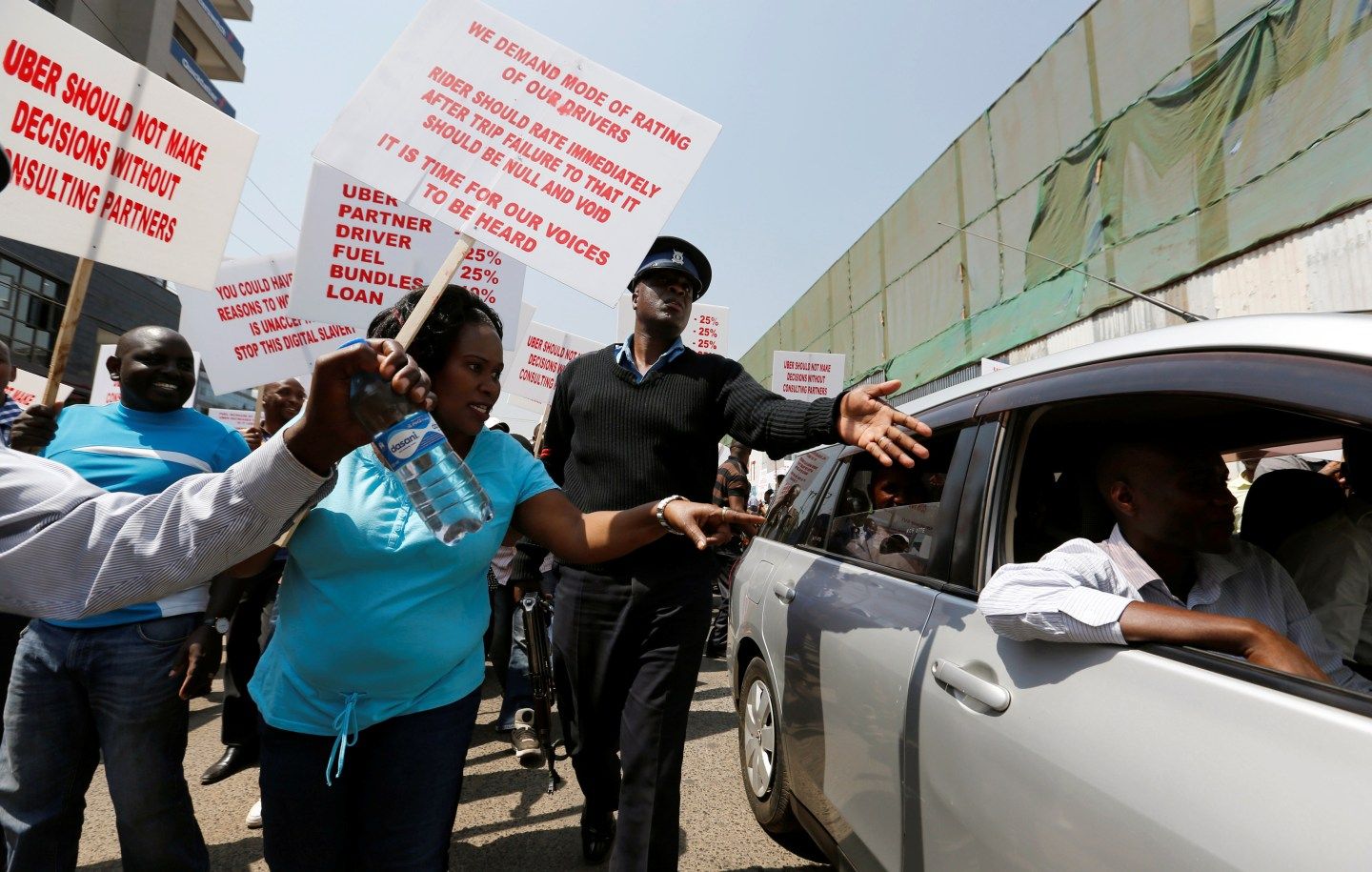 A policeman intervenes as Kenyan taxi drivers signed up to ride-hailing service Uber attempt to eject a passenger from an Uber operating taxis during a strike in Nairobi