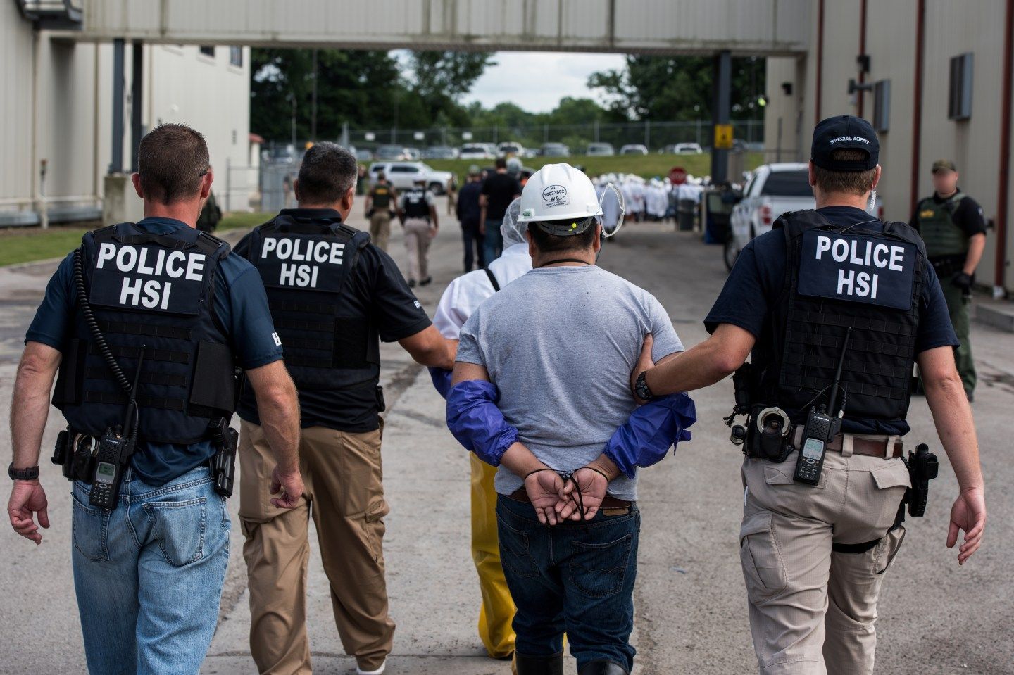 Special Agents lead workers and alleged immigration violators down a road