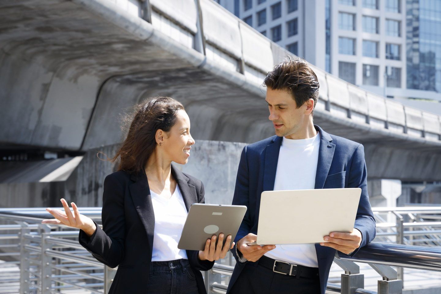 A man and woman stand looking at an iPad and piece of paper