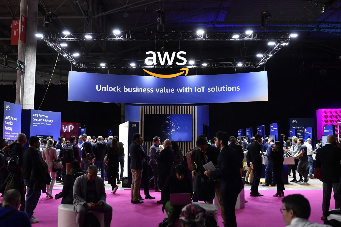 Conference goers in Barcelona mill about underneath an AWS sign.