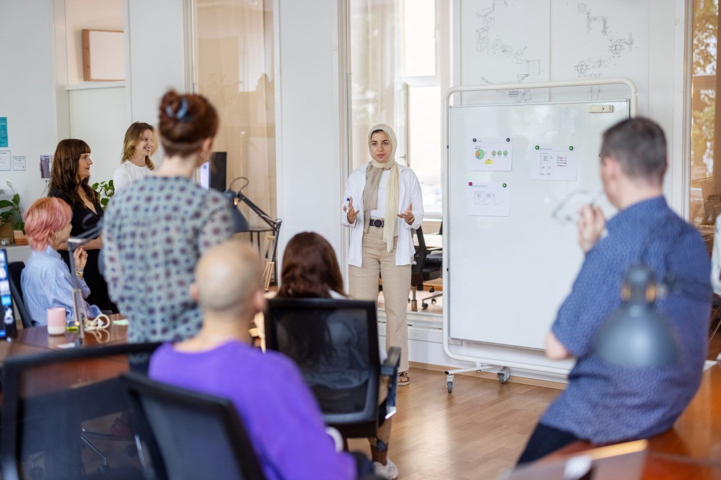 Woman stands in front of a room talking to a team of data experts.