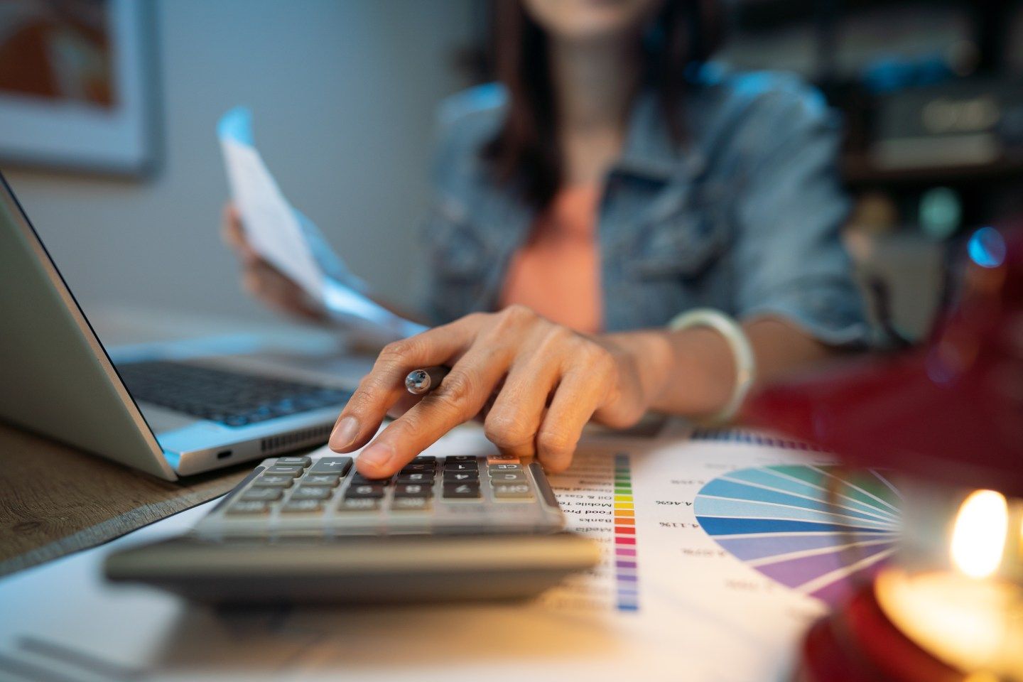 Close up of woman using a calculator with a paper in her other hand.