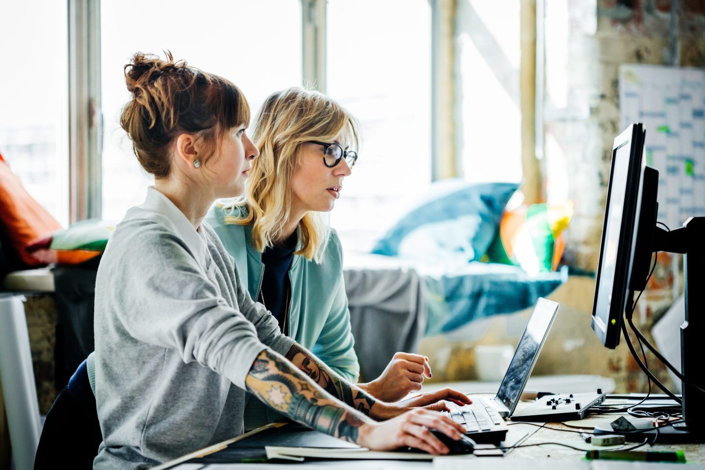 Two businesswomen work on a computer