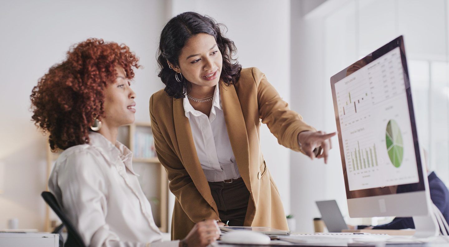 Women look at data on a displayed on a computer monitor.