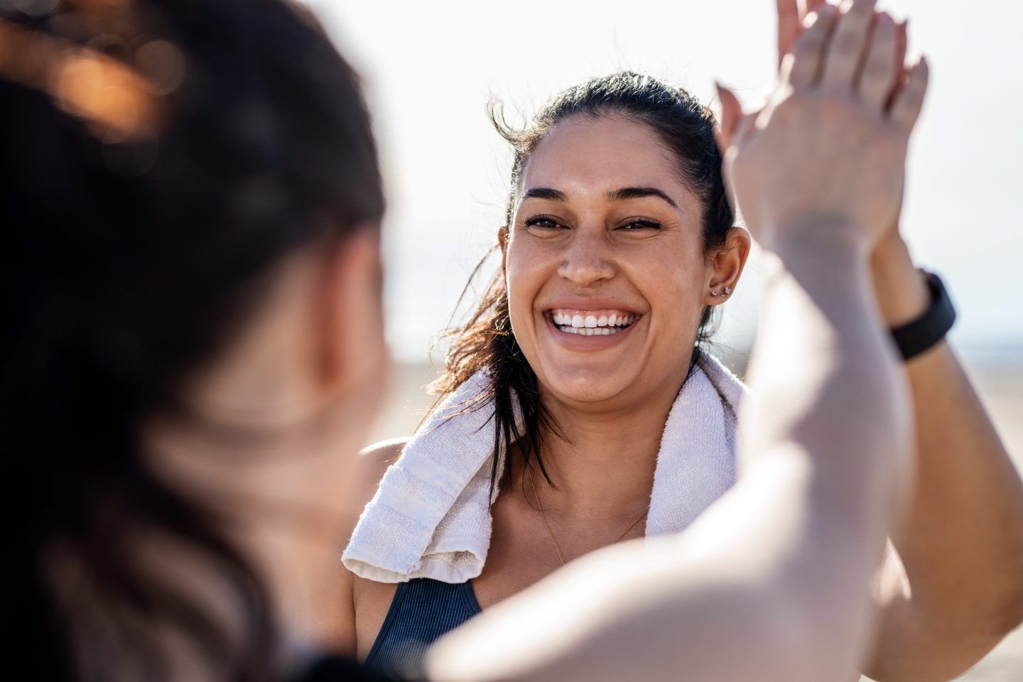 Smiling woman gives high five to her friend after exercising.