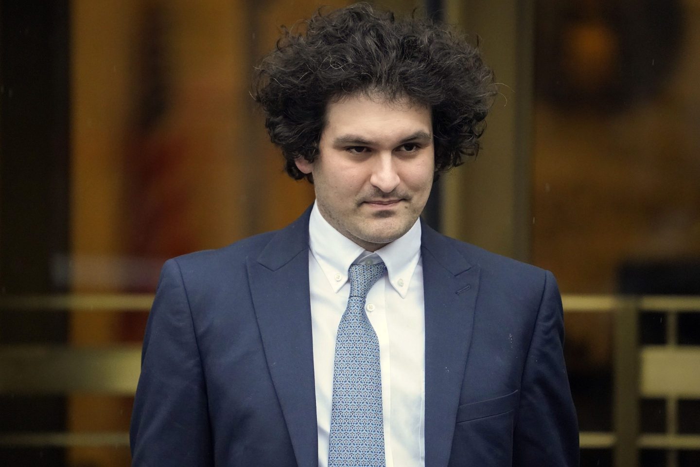 Sam Bankman-Fried is seen in court wearing a deep navy blue suit and a lighter blue tie with white dress shirt.