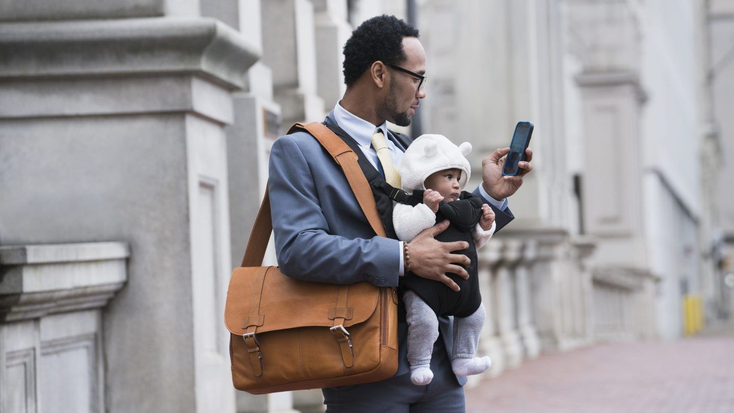 A dad working while holding a baby carrier