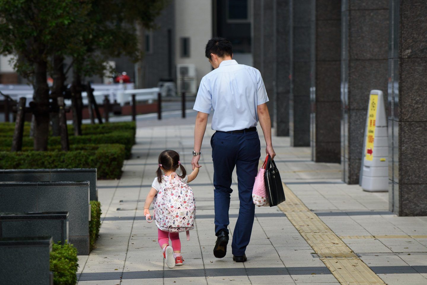 A Japanese father holds his daughter's hand walking down the street