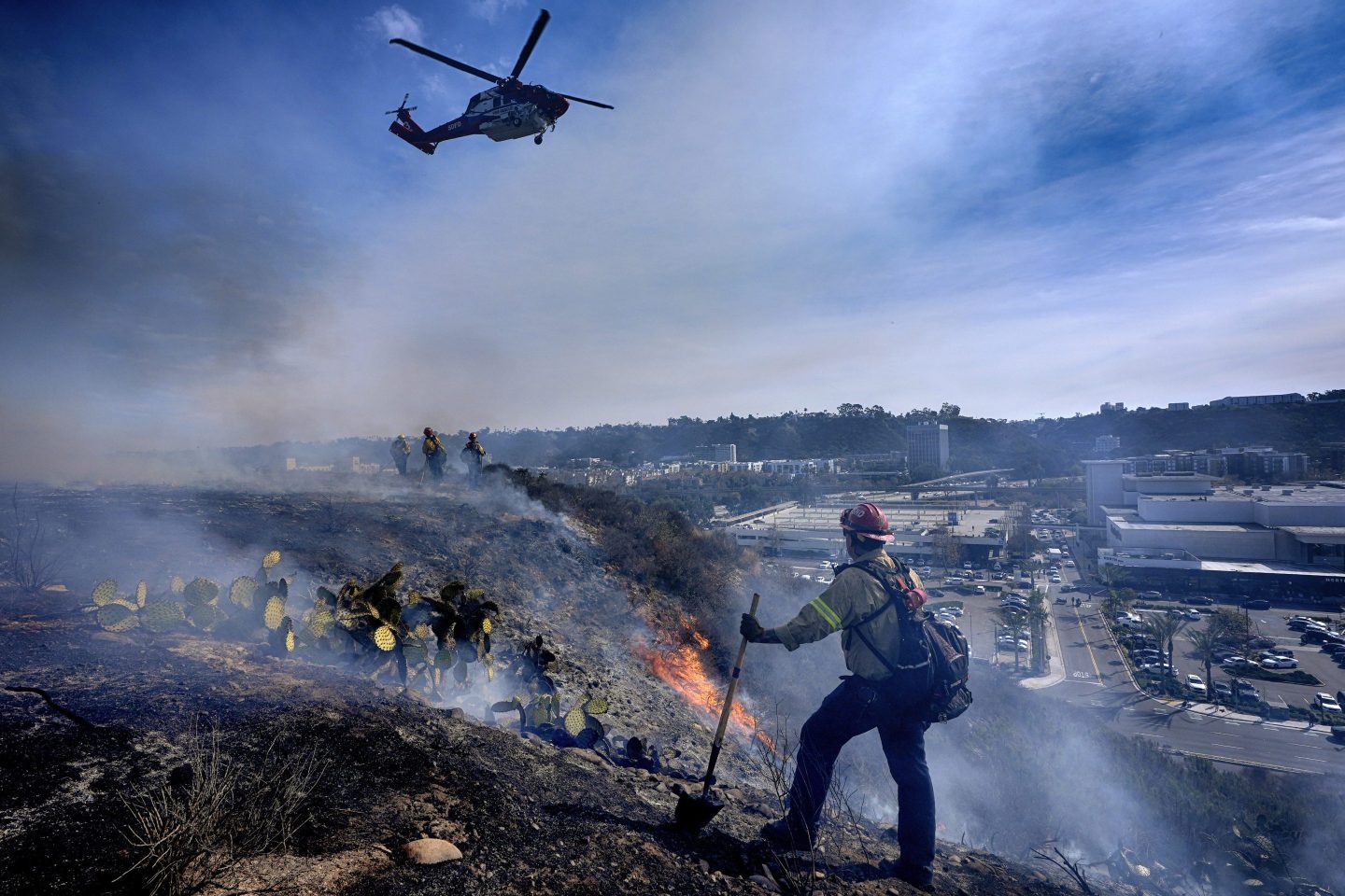 San Diego firefighters knock down a small brush along a hillside over the Mission Valley Shopping Mall in San Diego on Jan. 21, 2025.