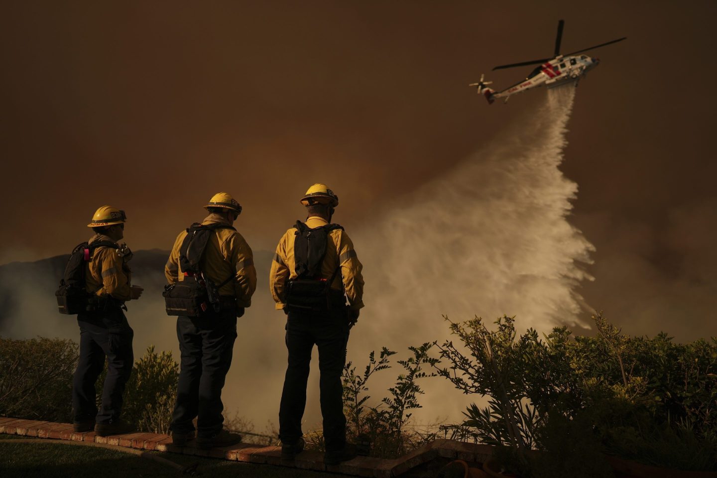 Water is dropped by helicopter on the Palisades Fire in Mandeville Canyon, Jan. 11, 2025, in Los Angeles.