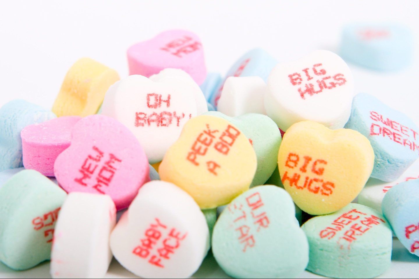 A pile of candy hearts with messages written on them for Valentine's Day
