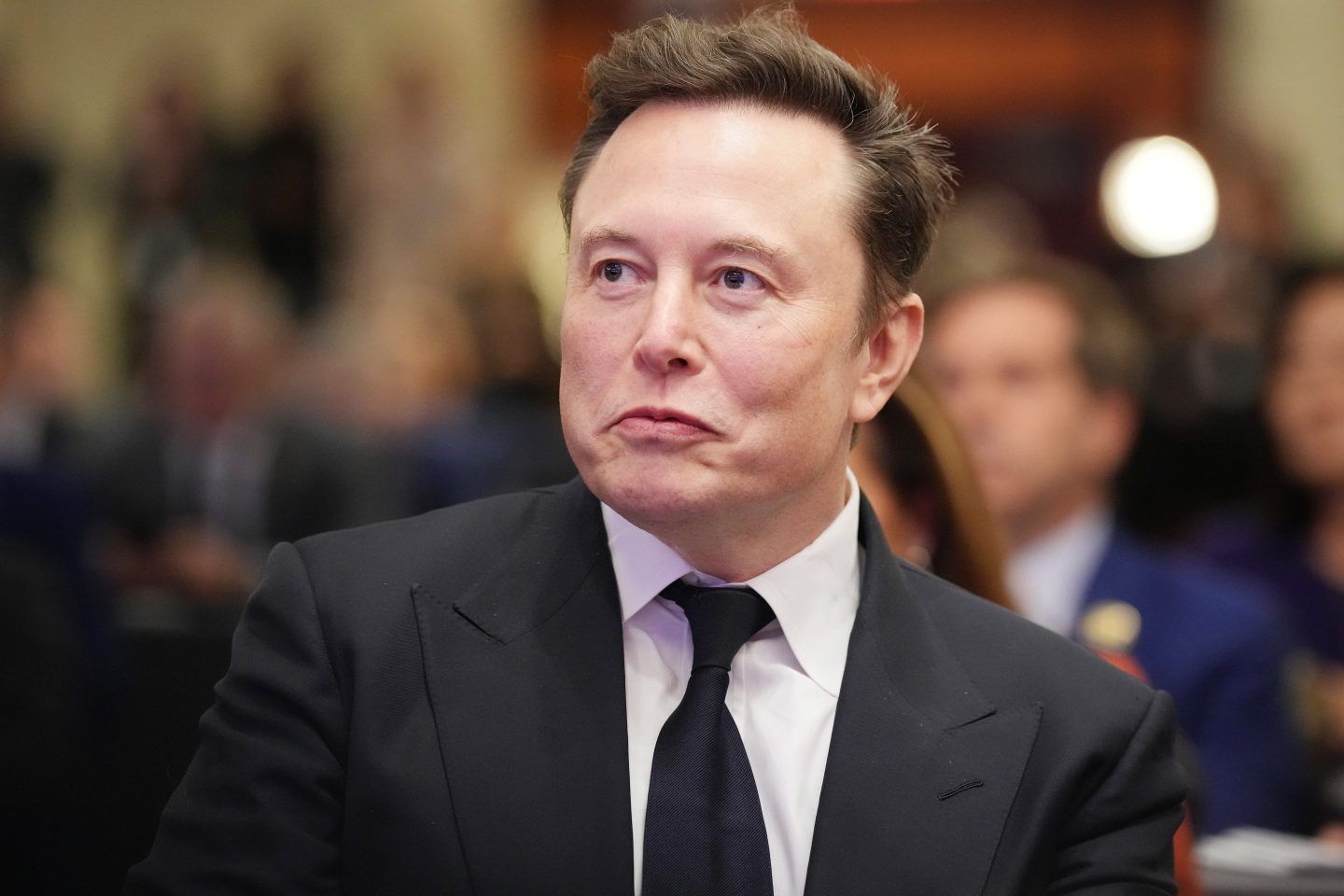 Elon Musk listens as U.S. President-elect Donald Trump addresses a House Republicans Conference meeting at the Hyatt Regency on Capitol Hill on November 13, 2024 in Washington, DC.