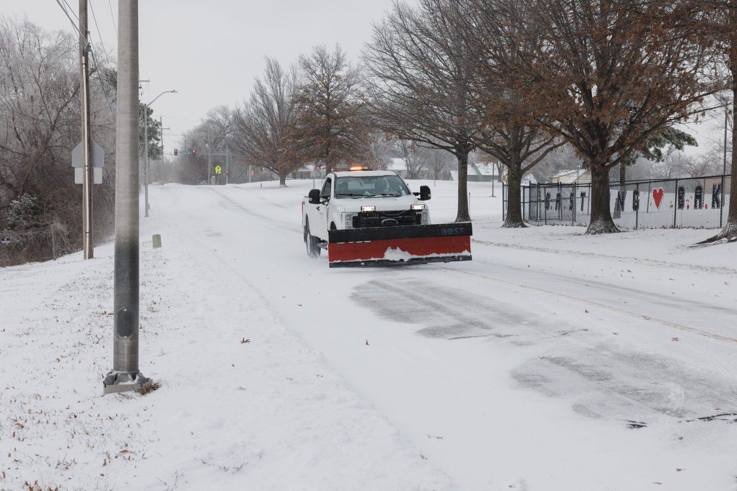 A county truck with a snowplow drives down a road in Kansas.