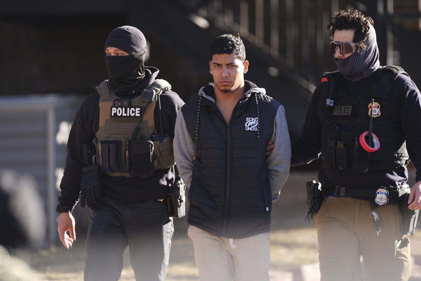 Law officials escort a suspect from an apartment to a waiting utility vehicle for transport during a raid on Feb. 5, 2025, in east Denver.