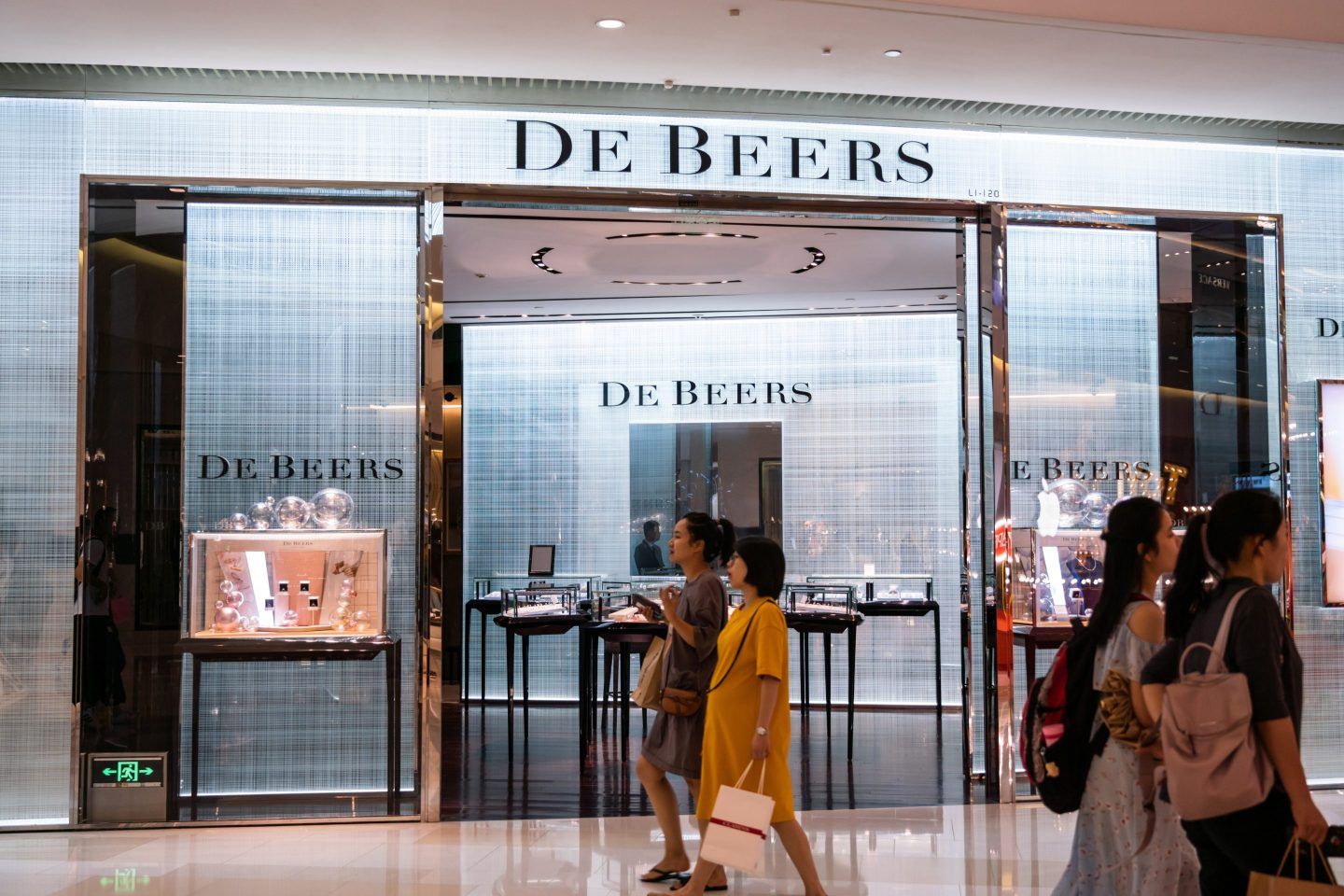 Pedestrians walk past a British multinational diamond mining and trading corporation De Beers store in Shanghai.