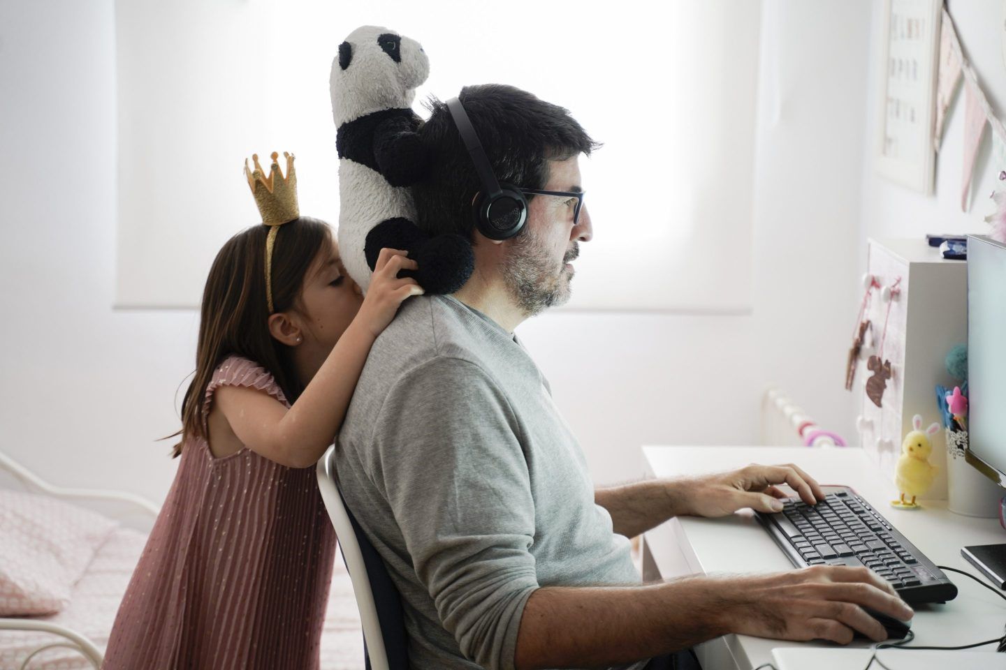 A person working remotely while a child plays with toys near them.