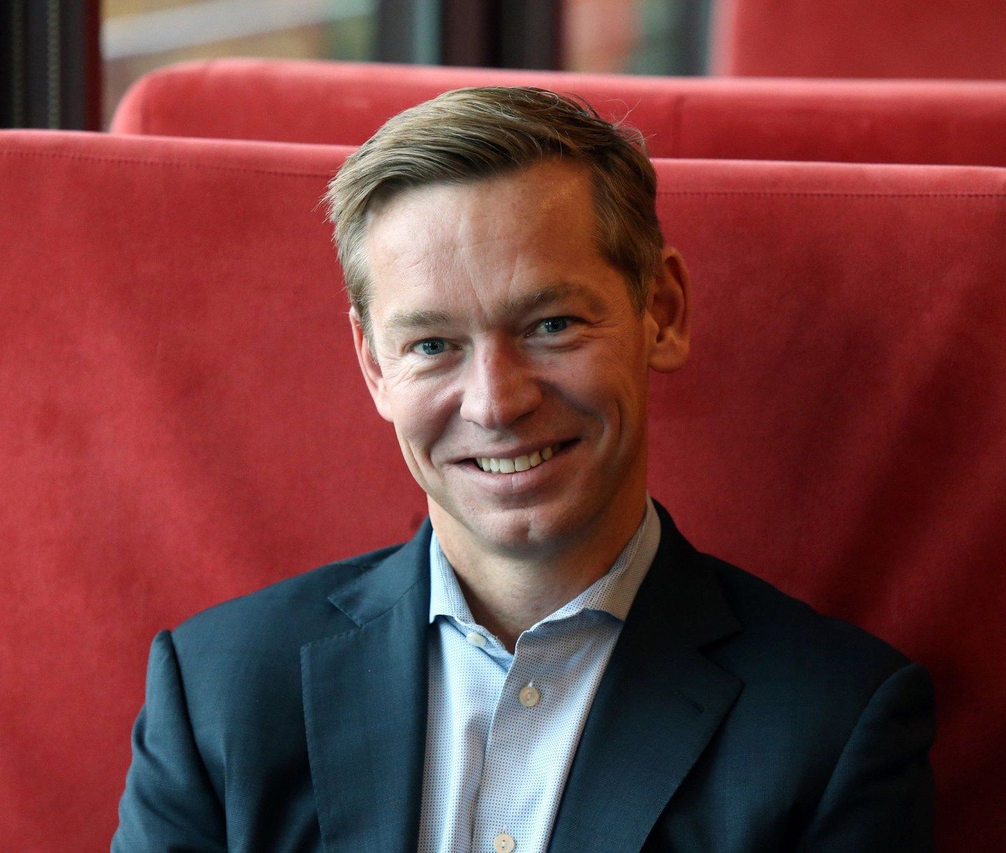 McDonald's CEO Chris Kempczinski poses while sitting in a red booth