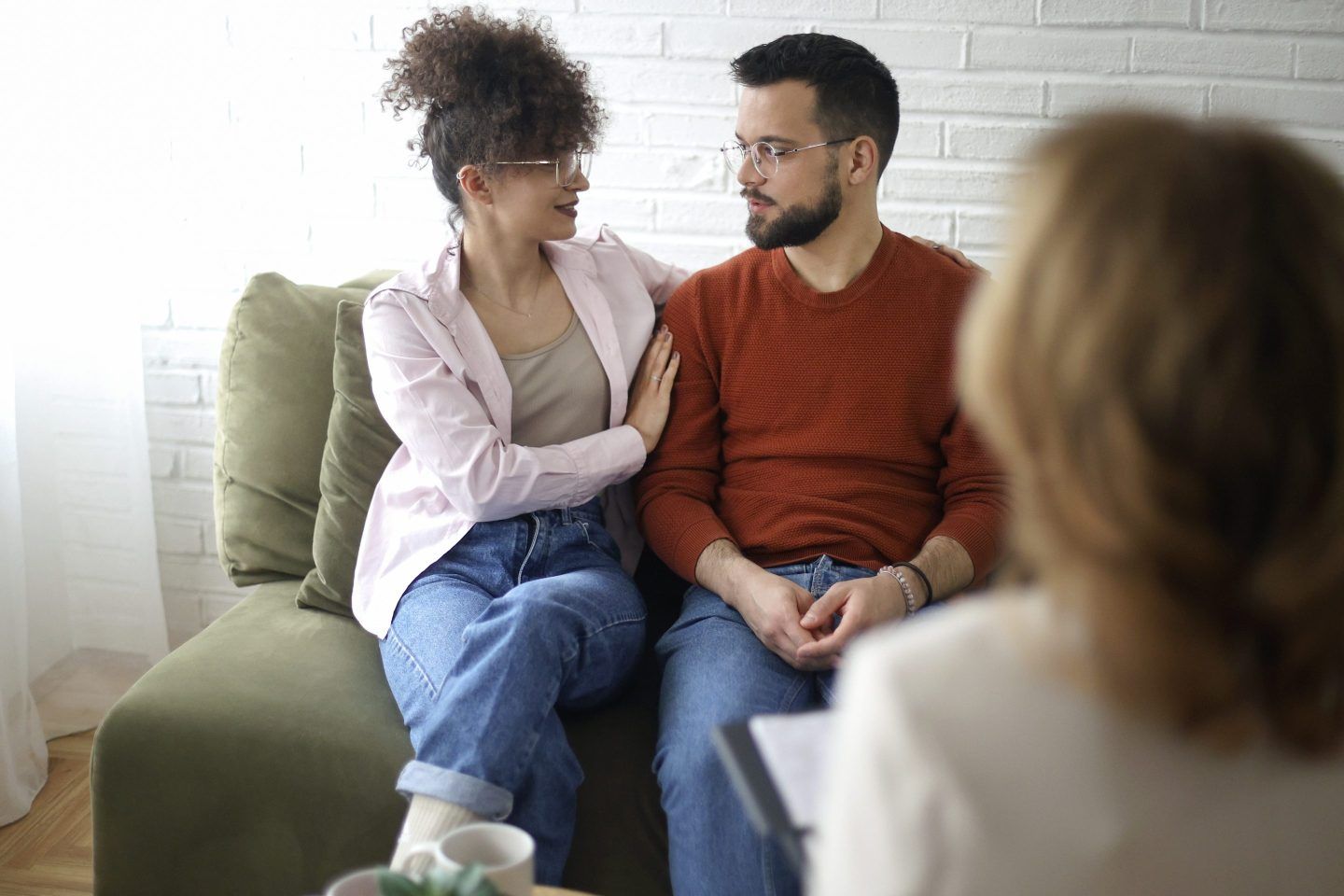 Woman and man on couch in background, back of woman who is assumed therapist in foreground.