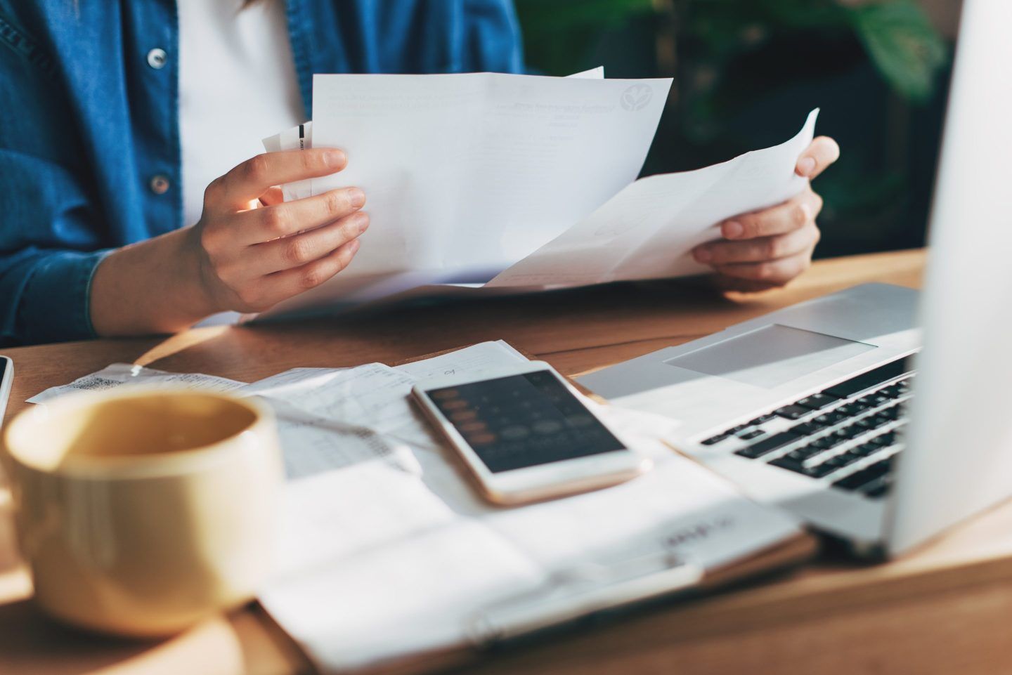 An individual looks over financial statements, sitting in front of a laptop and calculator app.