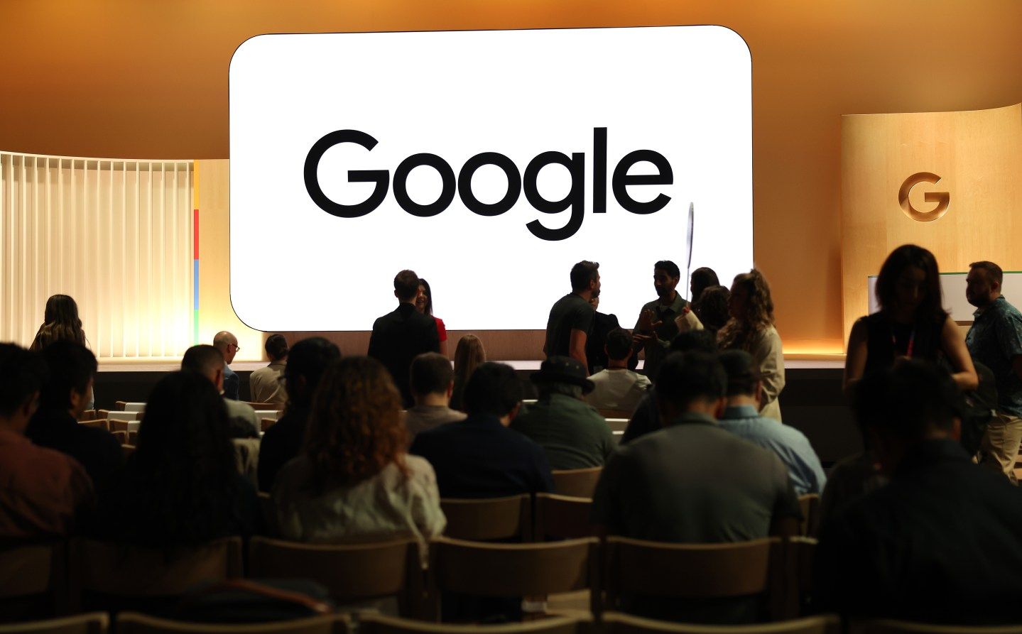 Google logo displayed on a screen with an audience below