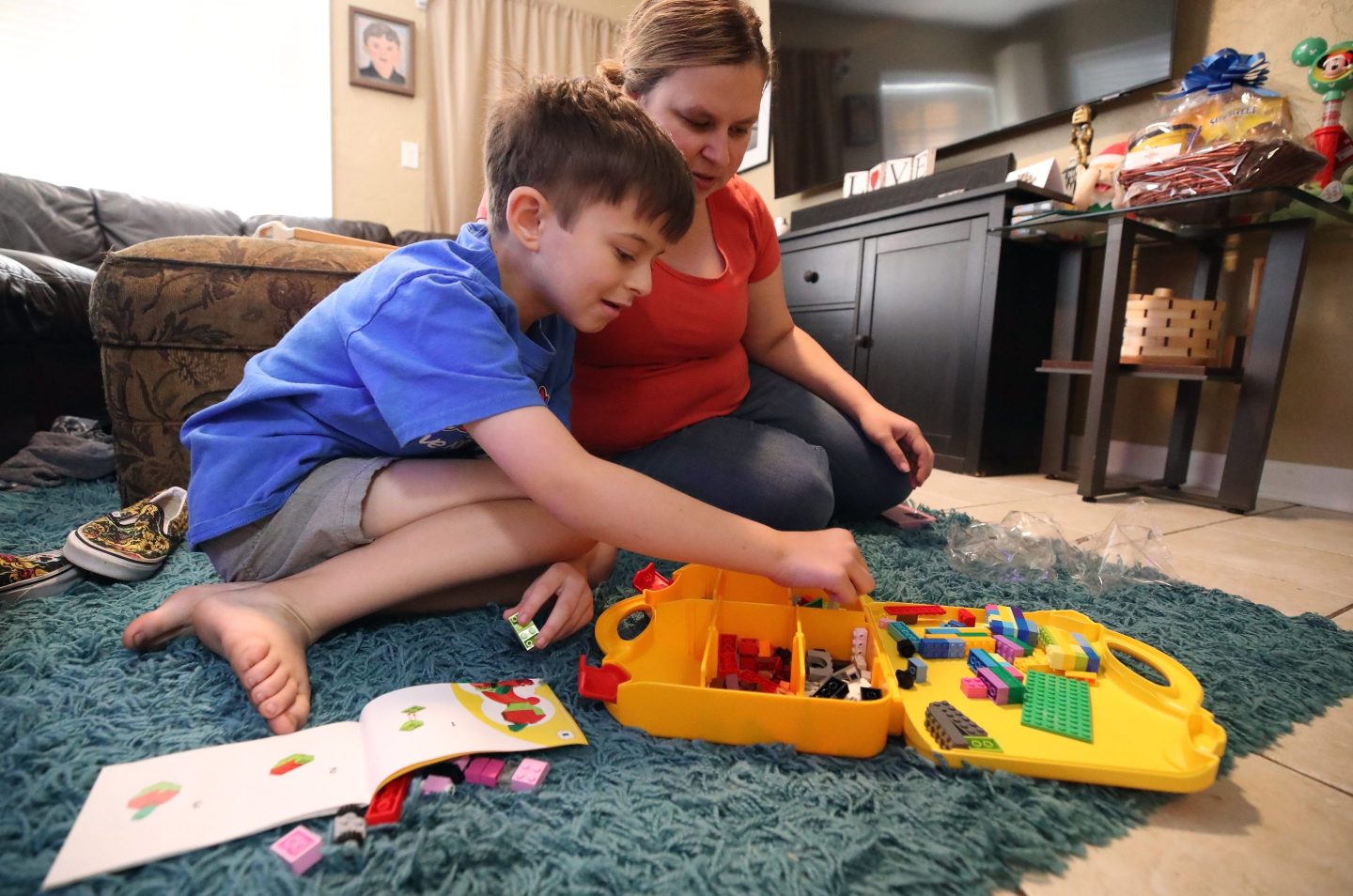 A kid playing with Legos on the floor with his mom