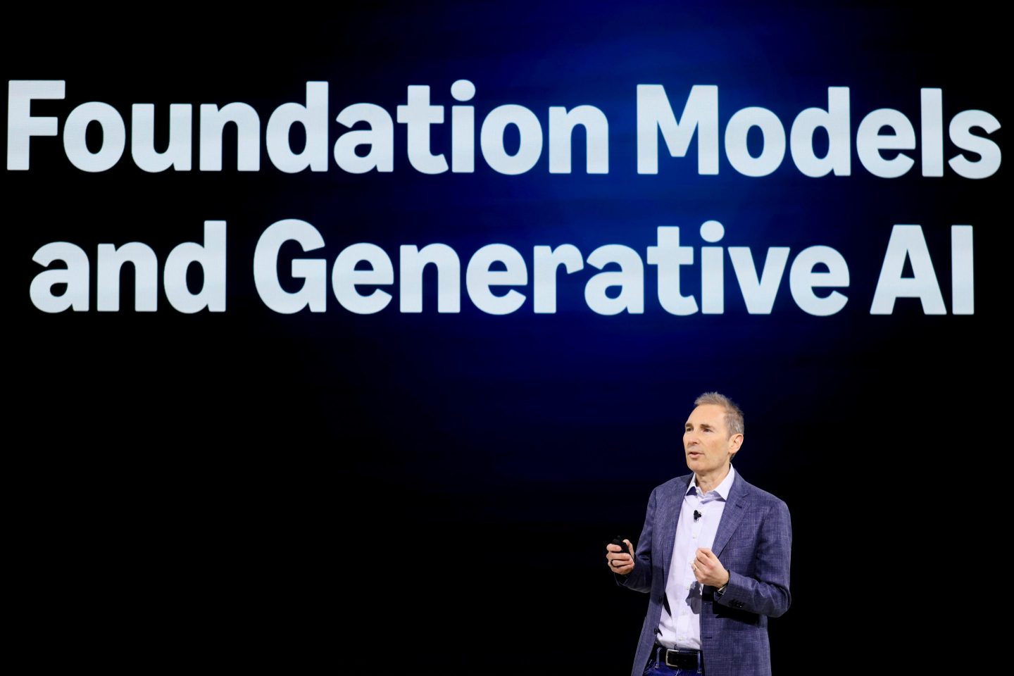 Amazon CEO Andy Jassy on stage in front of a screen that says "Foundation Models and Generative AI" as he introduces the new Amazon Alexa+.