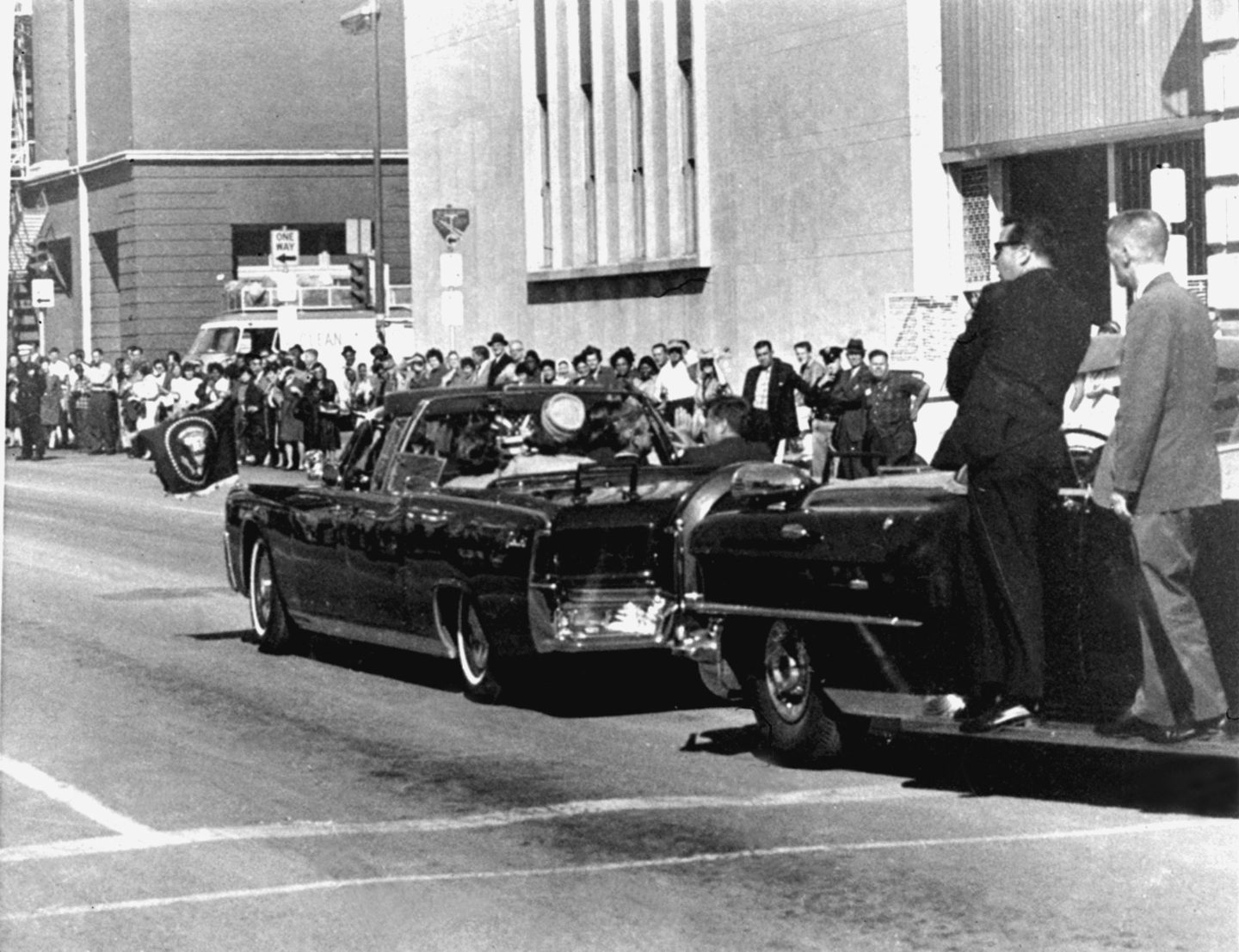 Secret servicemen standing on running boards follow the presidential limousine carrying President John F. Kennedy, right, rear seat, and first lady Jacqueline Kennedy, left, as well as Texas Gov. John Connally and his wife, Nellie, in Dallas, on Nov. 22, 1963.
