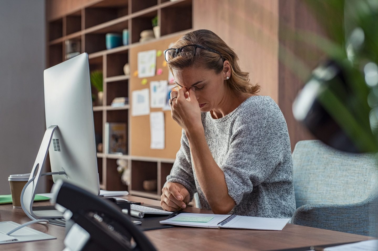 A woman rubs her eyes while sitting at a desk