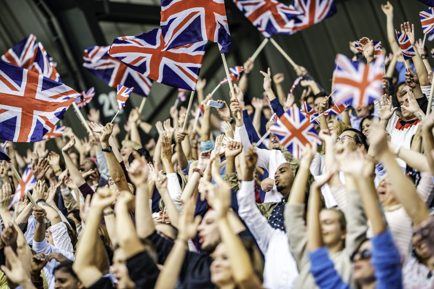 Large crowd in a stadium cheering and waving the flag of Great Britain
