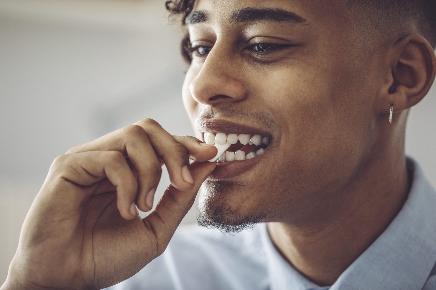 Closeup of man putting piece of chewing gum into his mouth