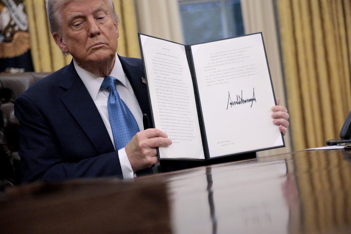 President Donald Trump holds up "Unleashing prosperity through deregulation," an executive order he signed on Jan. 31, 2025.